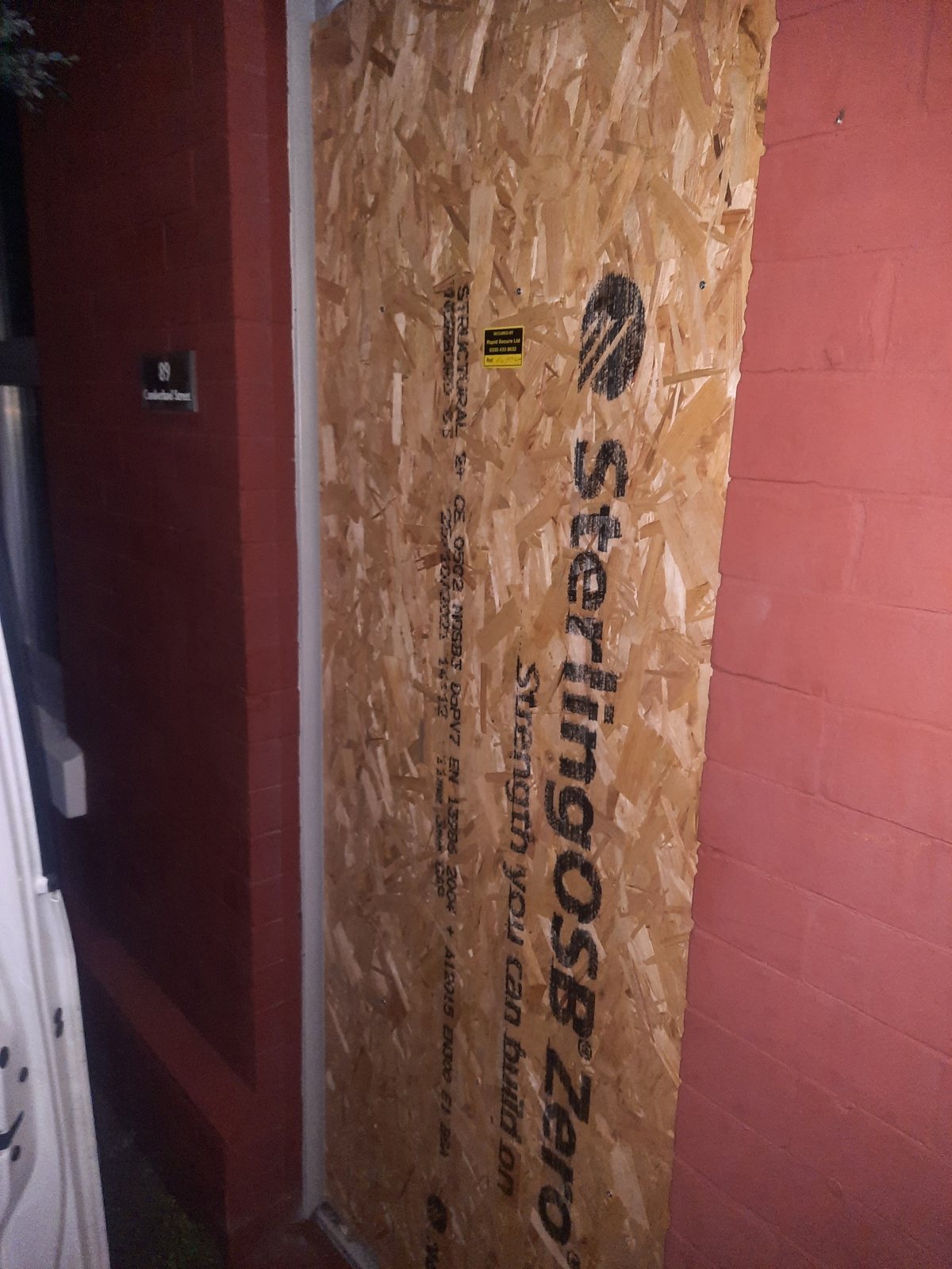 A doorway boarded over with a full sheet of timber board